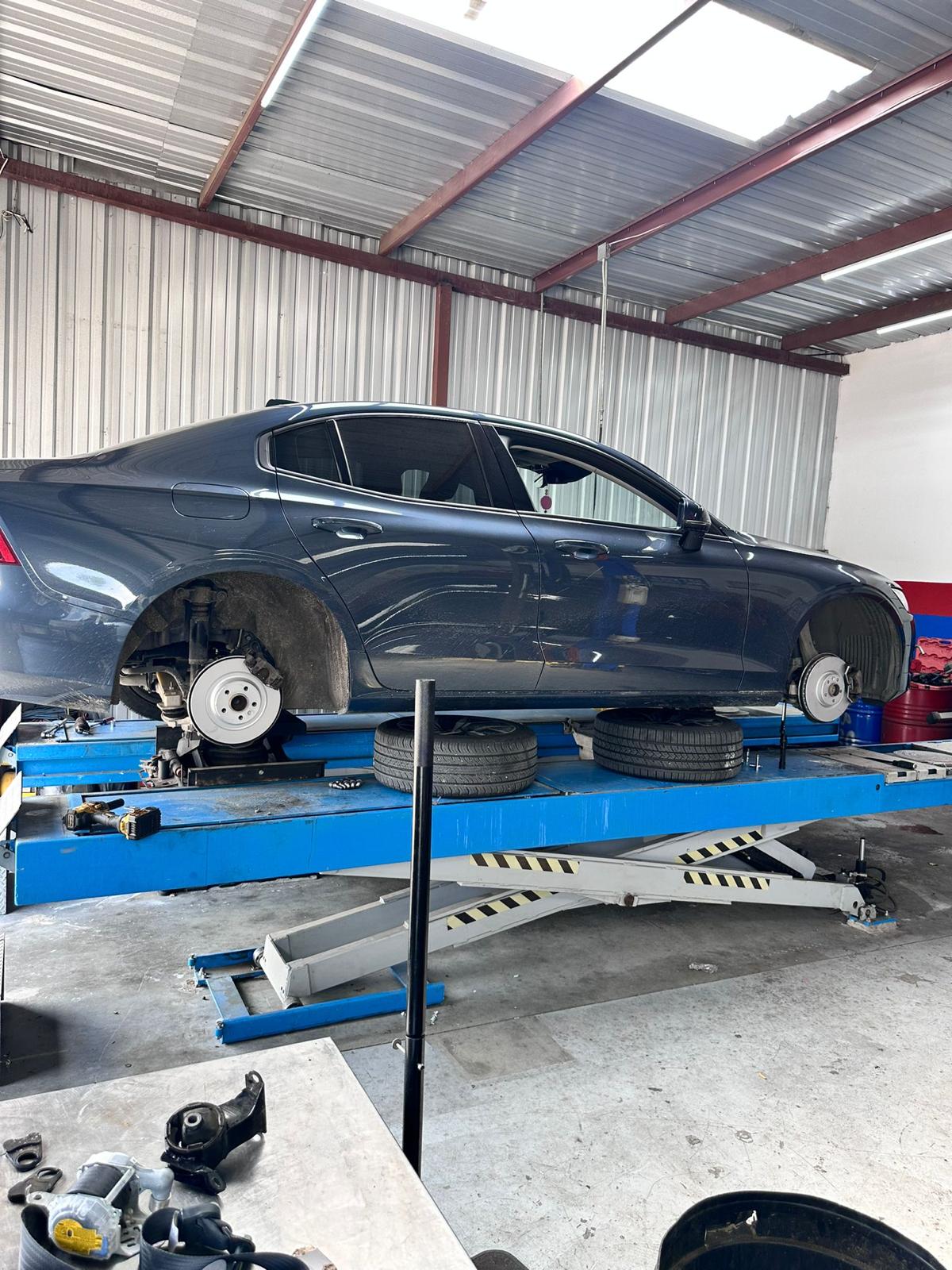 Black vehicle on a lift inside Sam Auto Repair & Collision