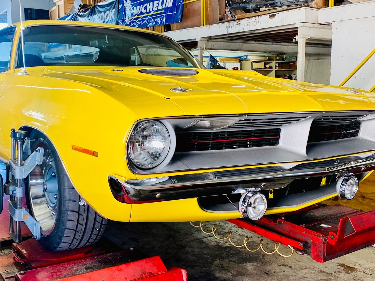 Yellow Plymouth on the wheel alignment rack at Mac Tires in Pompano Beach