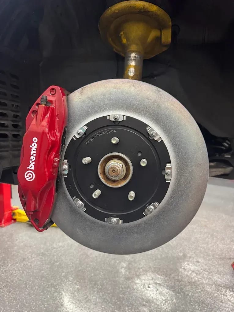 A red Brembo caliper and rotor during a brake job at John's Auto Care