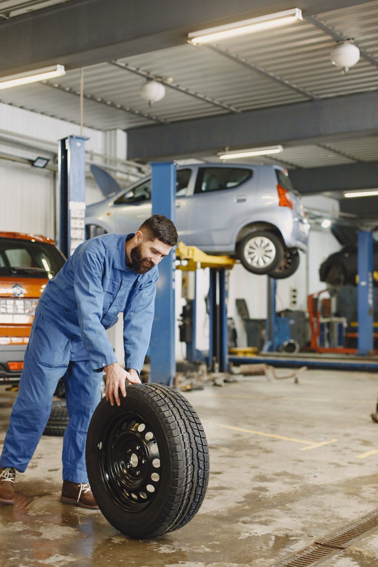 Mechanic handling a tire and wheel in a workshop