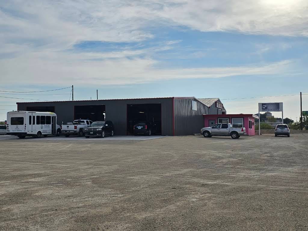 Vehicles outside Alamo's service bays and pink office in Fort Stockton