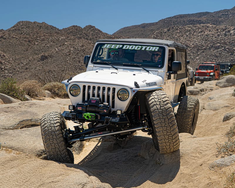 White open-cabin Jeep on rocky desert terrain