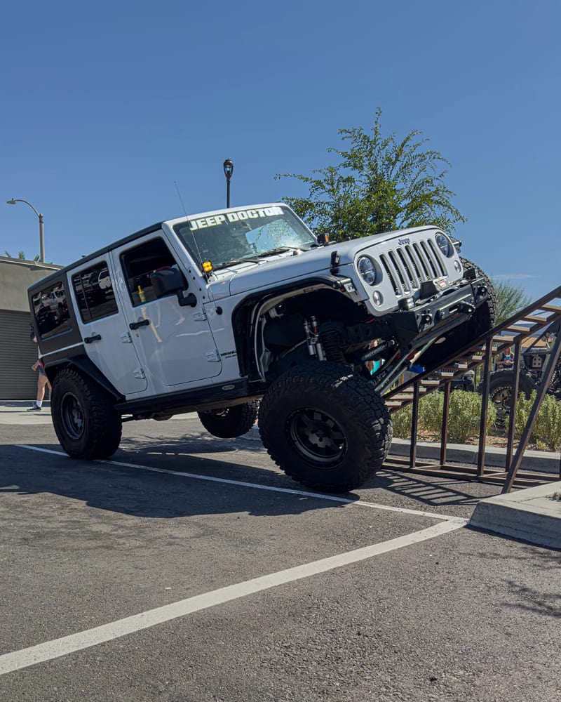 White Jeep showing suspension articulation on a ramp