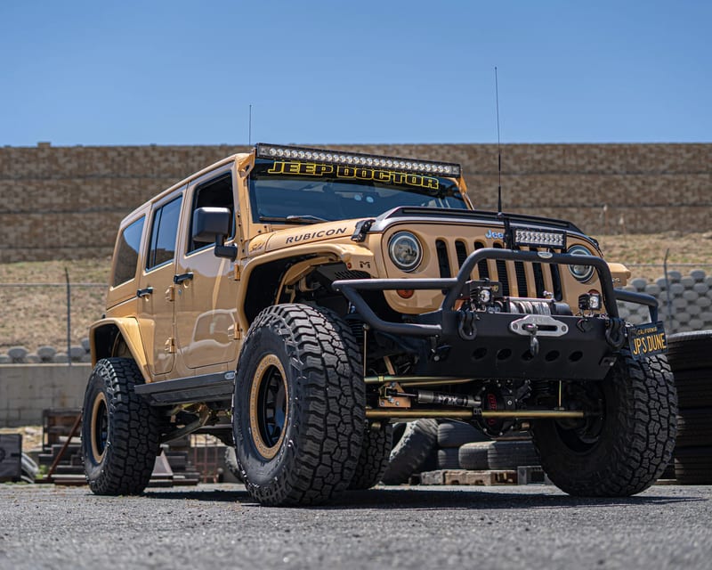 Gold four-door Jeep Wrangler with winch and off-road tires